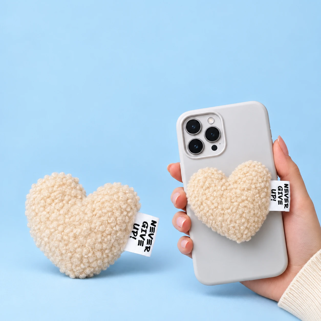 Cream curly-plush heart phone grip with original side label and illustrative closed phone placement, square composition