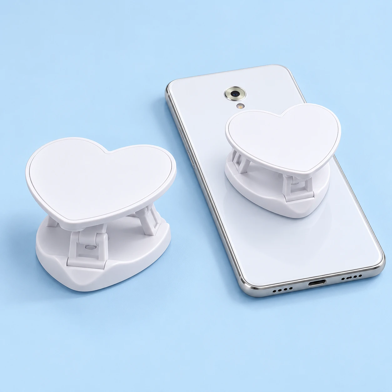 White heart fold-open phone grip, complete product and opened on a tabletop-supported phone back