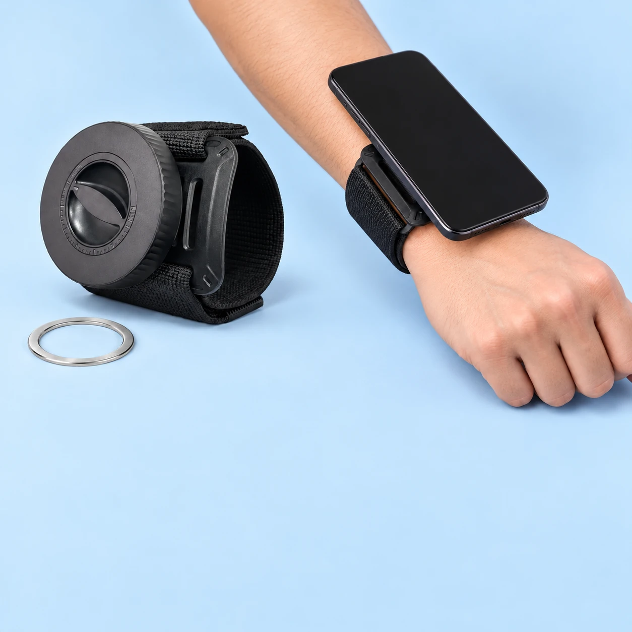 Black wide-cuff magnetic wrist phone holder and supplied receiver ring on pale blue, with illustrative stationary wrist-mounted phone use, square composition