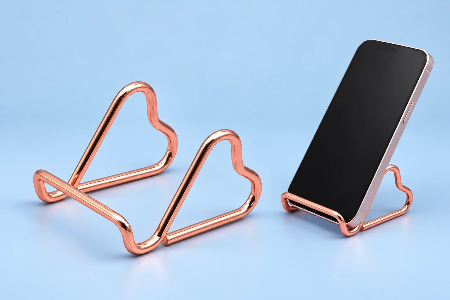 Rose-gold twin side-heart wire phone stand, isolated and supporting a portrait phone