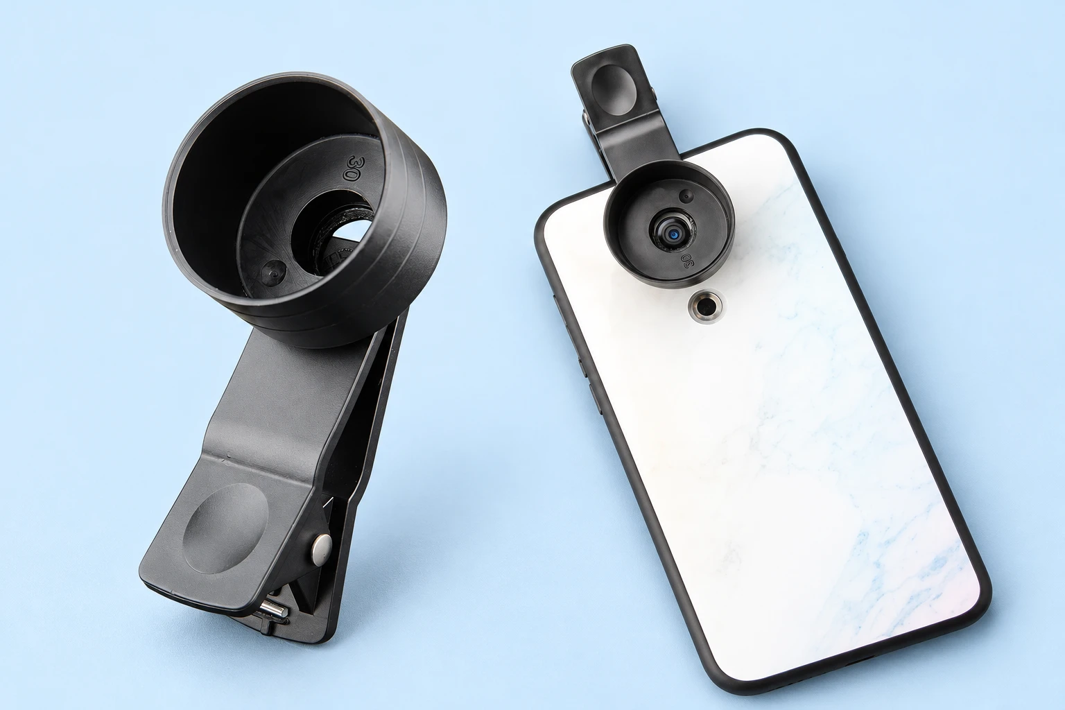 Complete black spring camera-edge clip with short 30 mm eyepiece cup at left; the same clip and cup attached over a demonstration phone rear camera at right on pale blue. Phone not included.