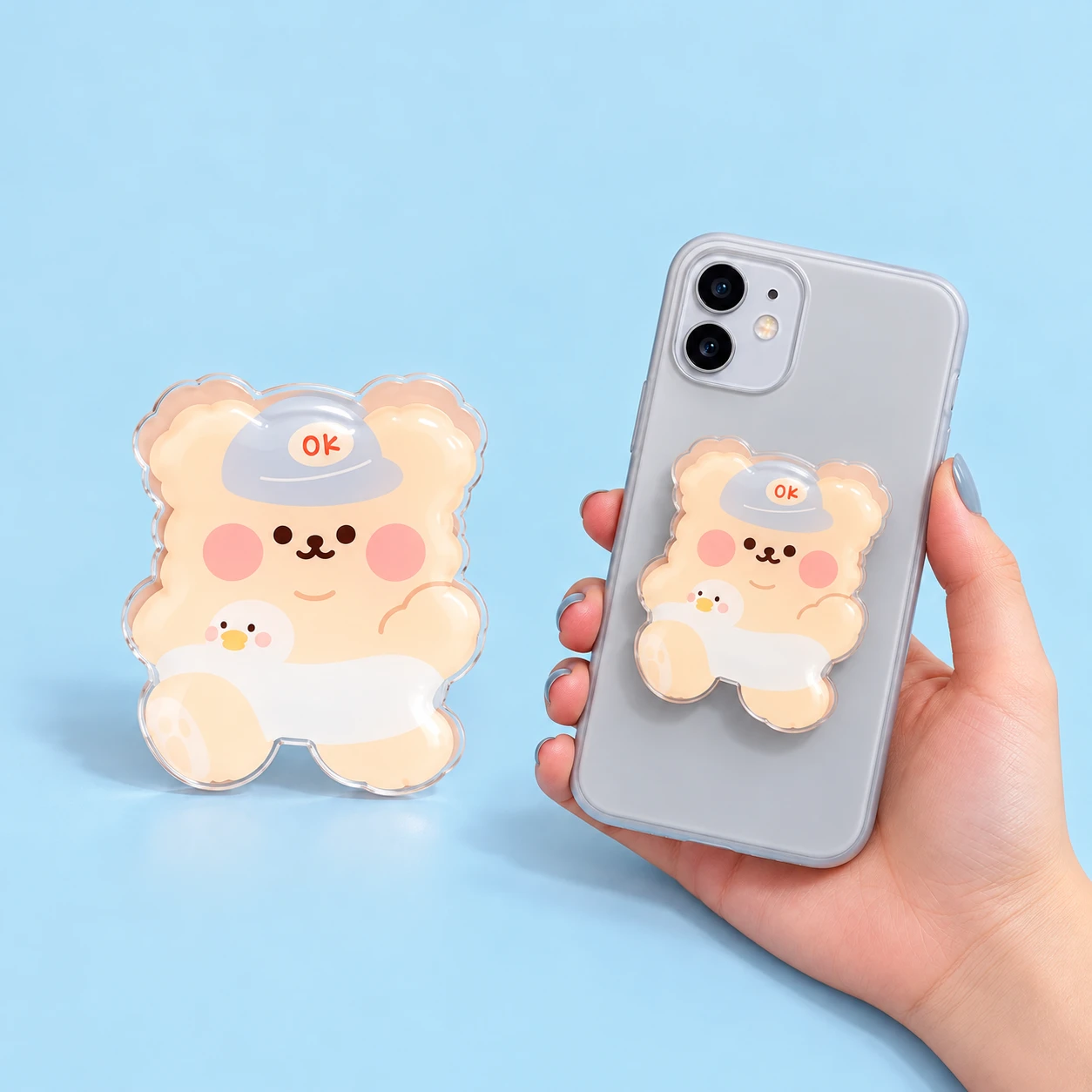 Blushing bear acrylic phone grip with gray OK hat and duck swim ring, shown in closed phone mounting, square composition