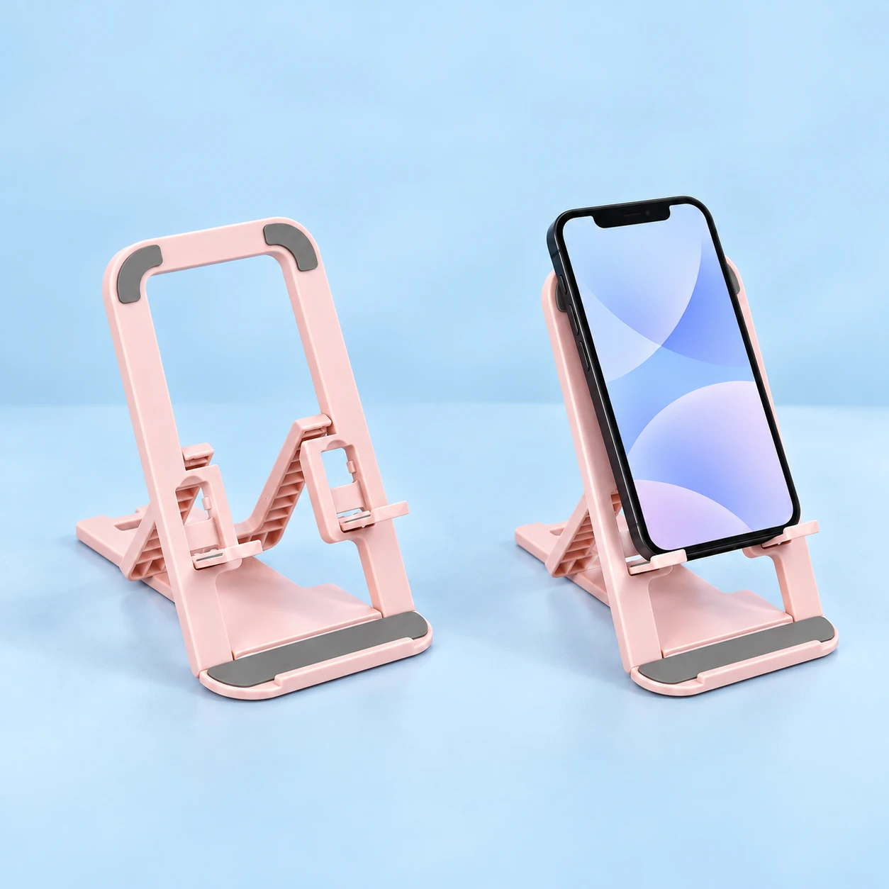 Undecorated pastel pink open-frame folding stand with two raised phone ledges, square composition