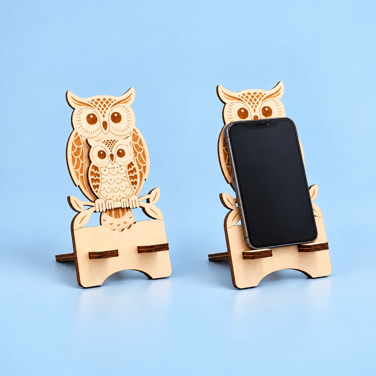 Parent-and-chick owl wooden phone stand with flat support tabs and illustrative portrait phone use, square composition