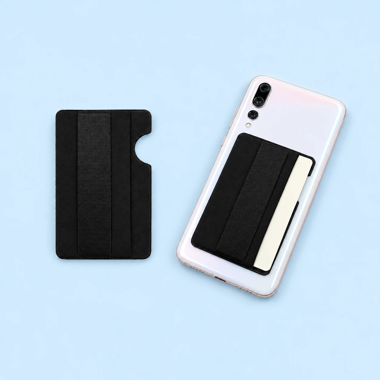 Black side-entry phone card pocket with flat elastic band, shown complete and empty on the left and mounted flat on a stationary phone with a blank demonstration card on the right against a pale-blue background., square composition