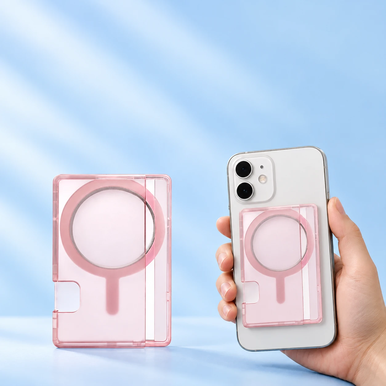 Frosted-pink side-access magnetic phone card holder shown complete and empty on the left and attached flat behind a hand-held phone on the right against a pale-blue background., square composition