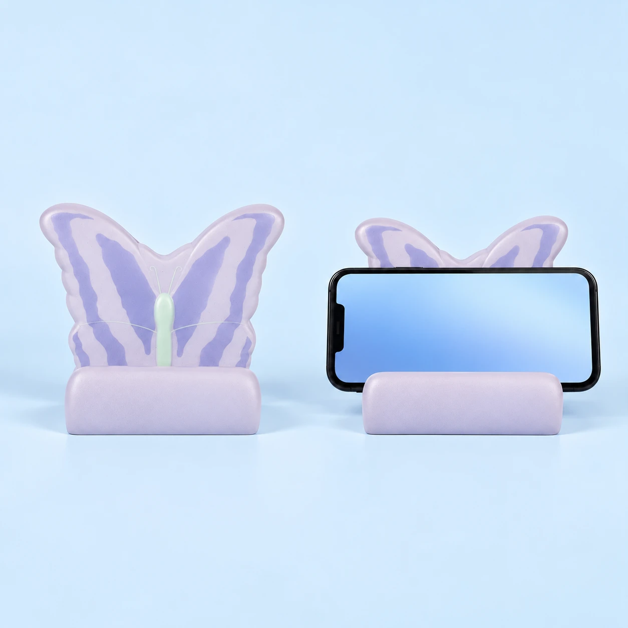 Lilac and cream molded foam butterfly phone cradle with pale mint center, shown empty and in an intended landscape-phone illustration, square composition