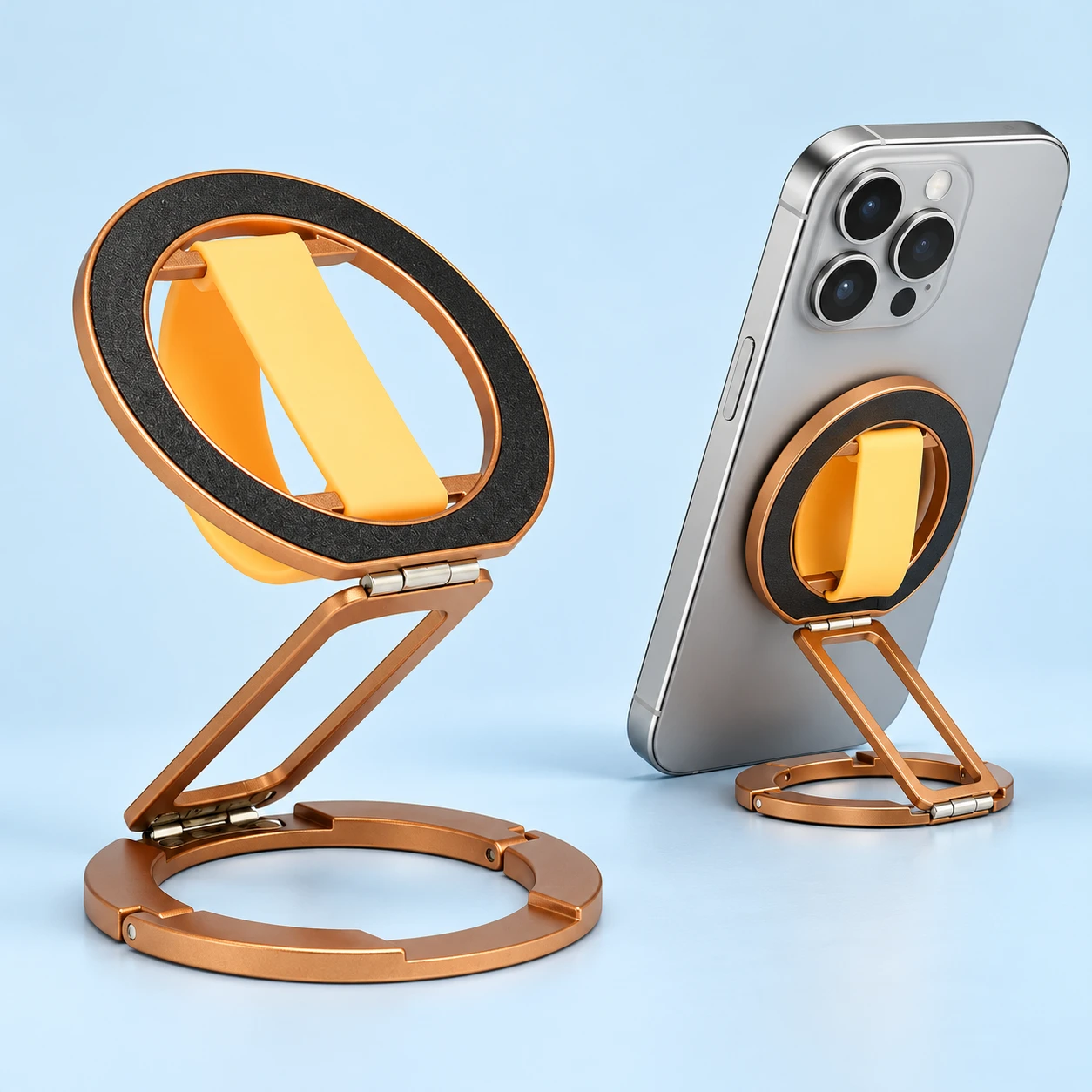 Gold folding phone finger-band holder with cream-yellow band, hinged bridge and segmented annular foot, shown complete and in compatible magnetic-phone support use.