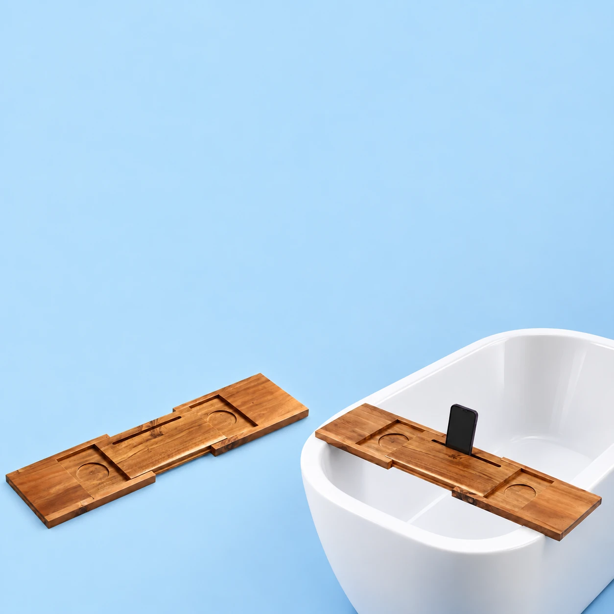 Complete brown extending wooden phone tray empty at left; the same original sliding tray spans suitable rims of a dry empty bathtub at right with one demonstration portrait phone seated in its original center groove, against pale blue. Phone and bathtub are not included., square composition