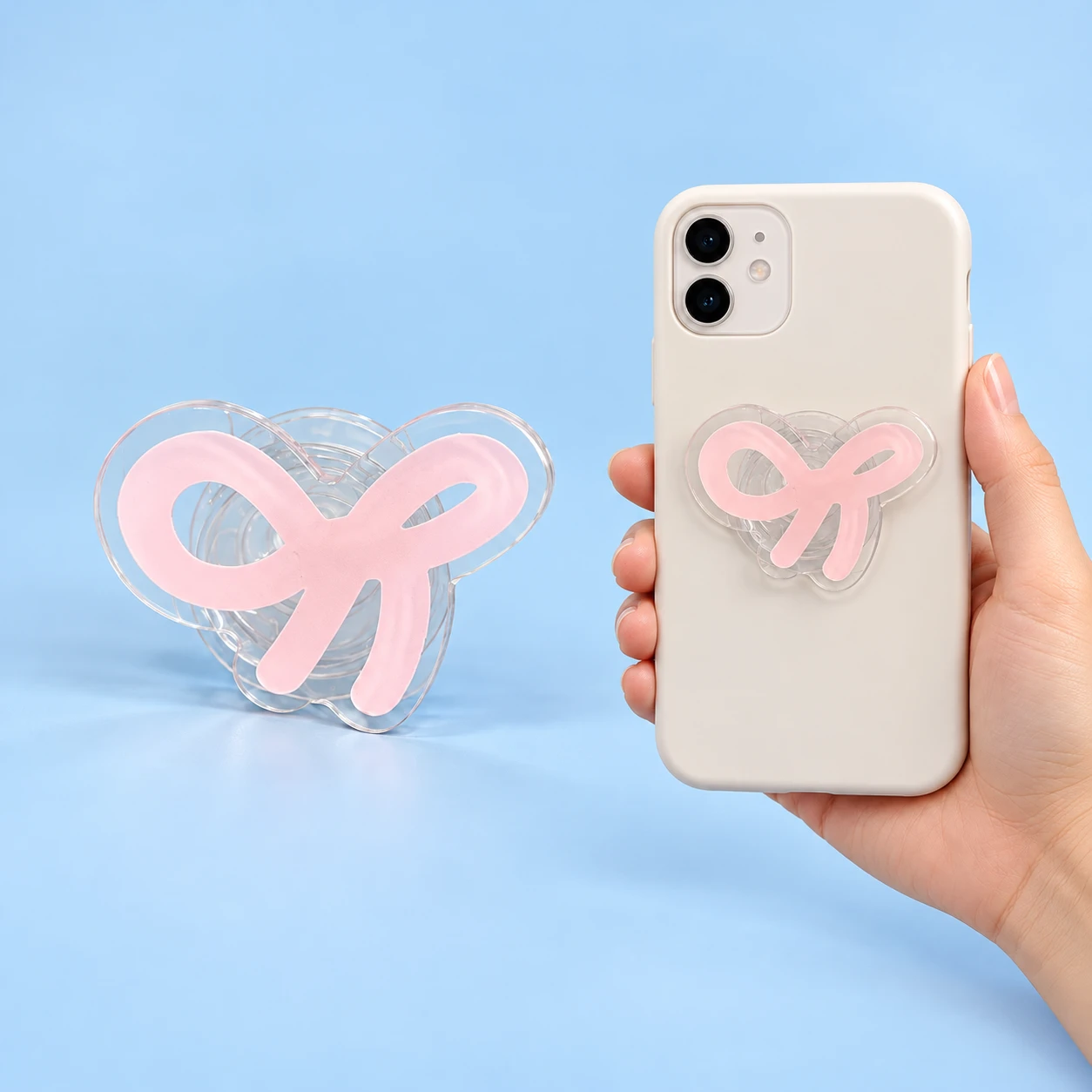 Transparent contour-cut pink ribbon phone grip shown complete and in a closed phone-case placement illustration, square composition