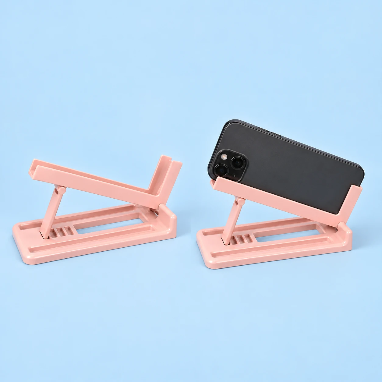 Pastel pink side-tilting rail phone stand with notched base and supported landscape phone, square composition