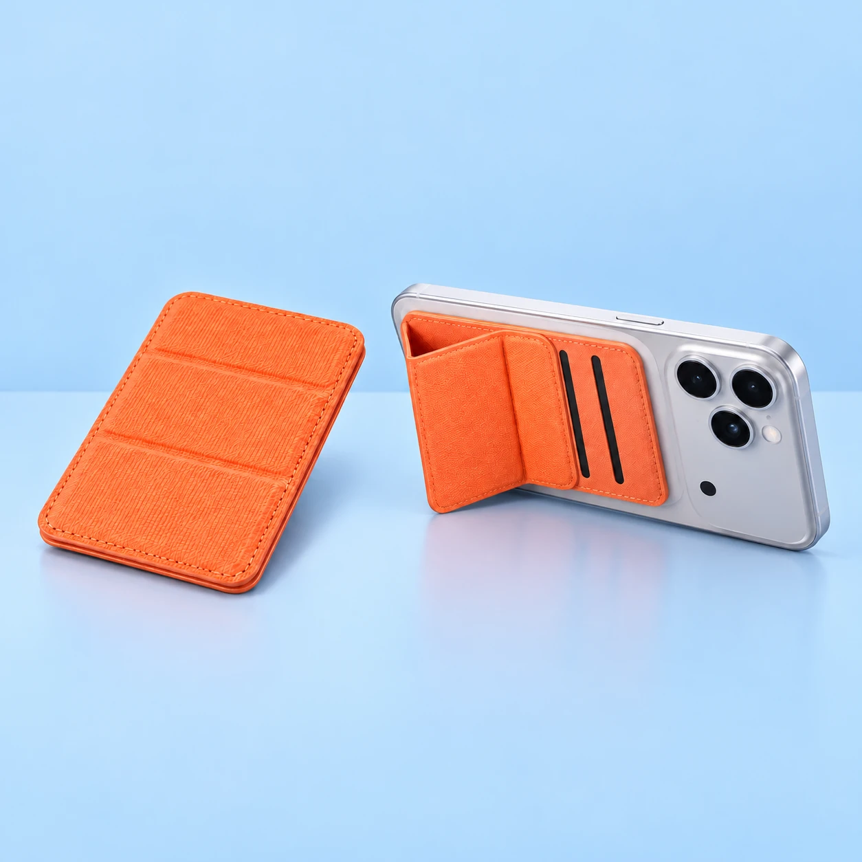 Orange three-fold magnetic phone wallet shown closed on the left and mounted behind a stationary landscape phone with its original side-folding cover on the right against a pale-blue background., square composition