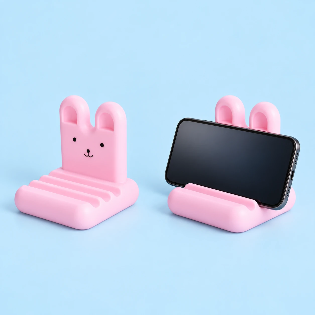 Pastel pink fixed rabbit phone stand with three front grooves, shown alone and supporting a landscape phone, square composition