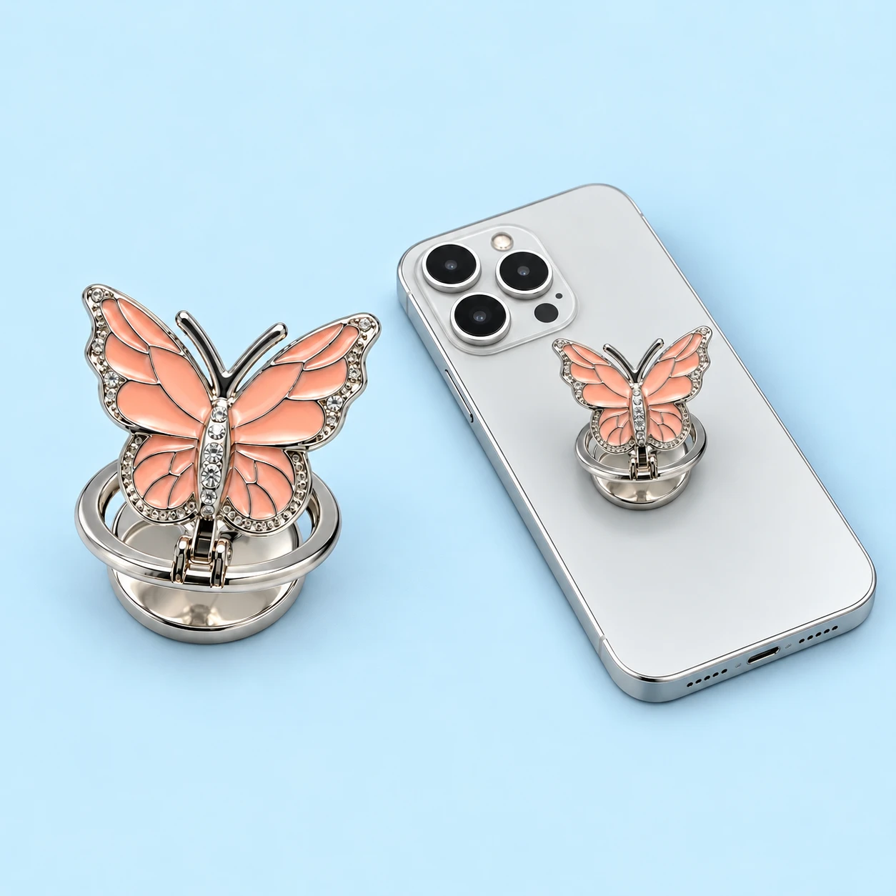 Peach pink segmented butterfly folding phone ring holder shown complete and mounted on a phone, square composition
