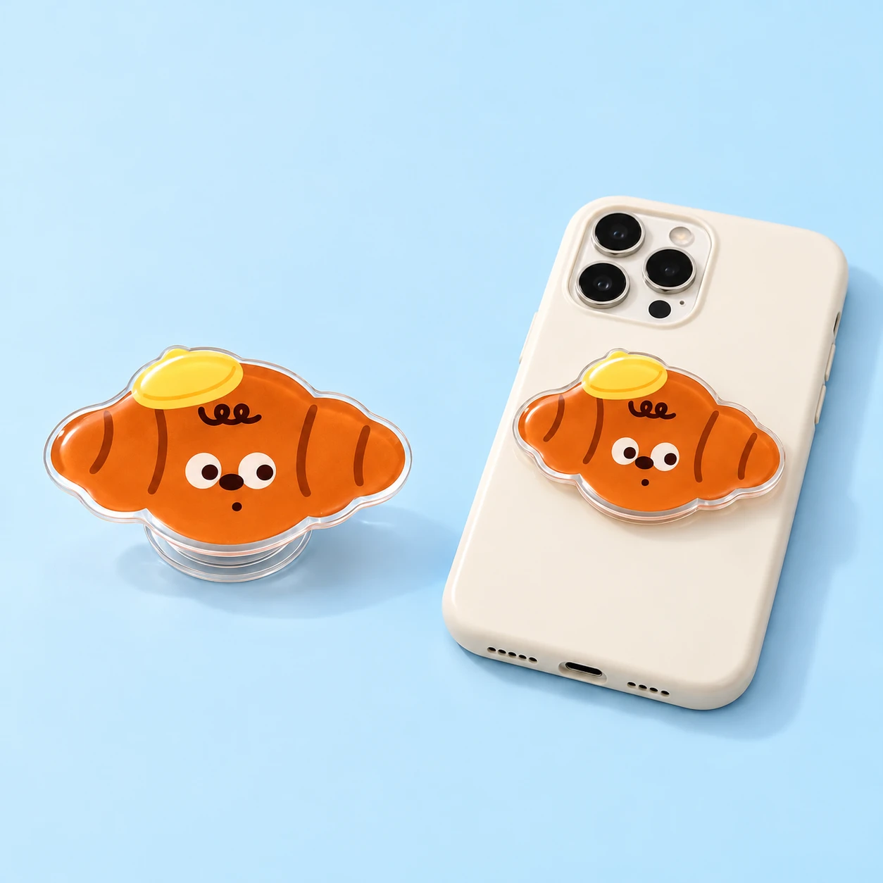 Yellow-cap croissant contour-cut acrylic phone grip shown alone and closed on a phone case, square composition