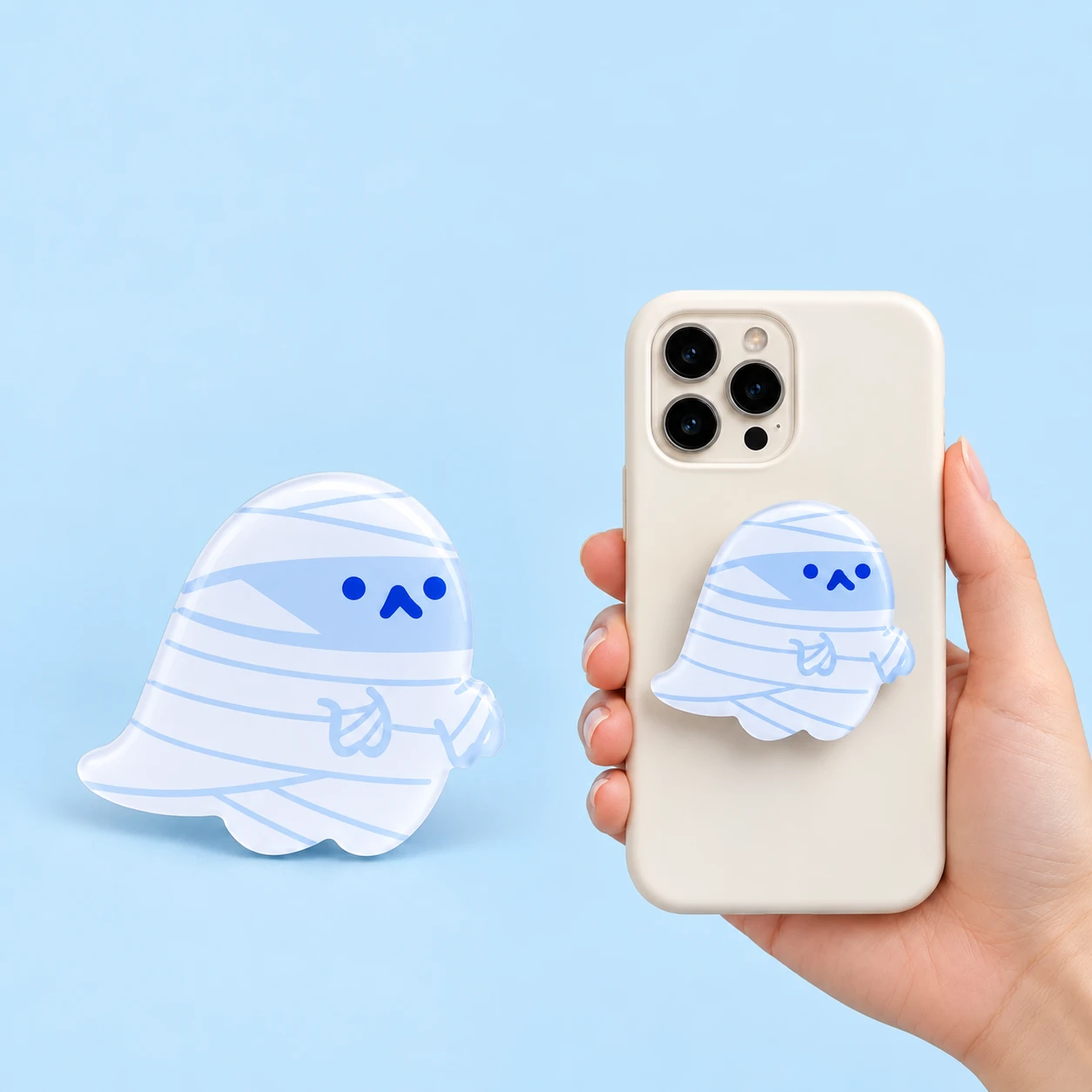 White mummy ghost expandable phone grip with pale-blue bandage print and closed phone-back placement, square composition