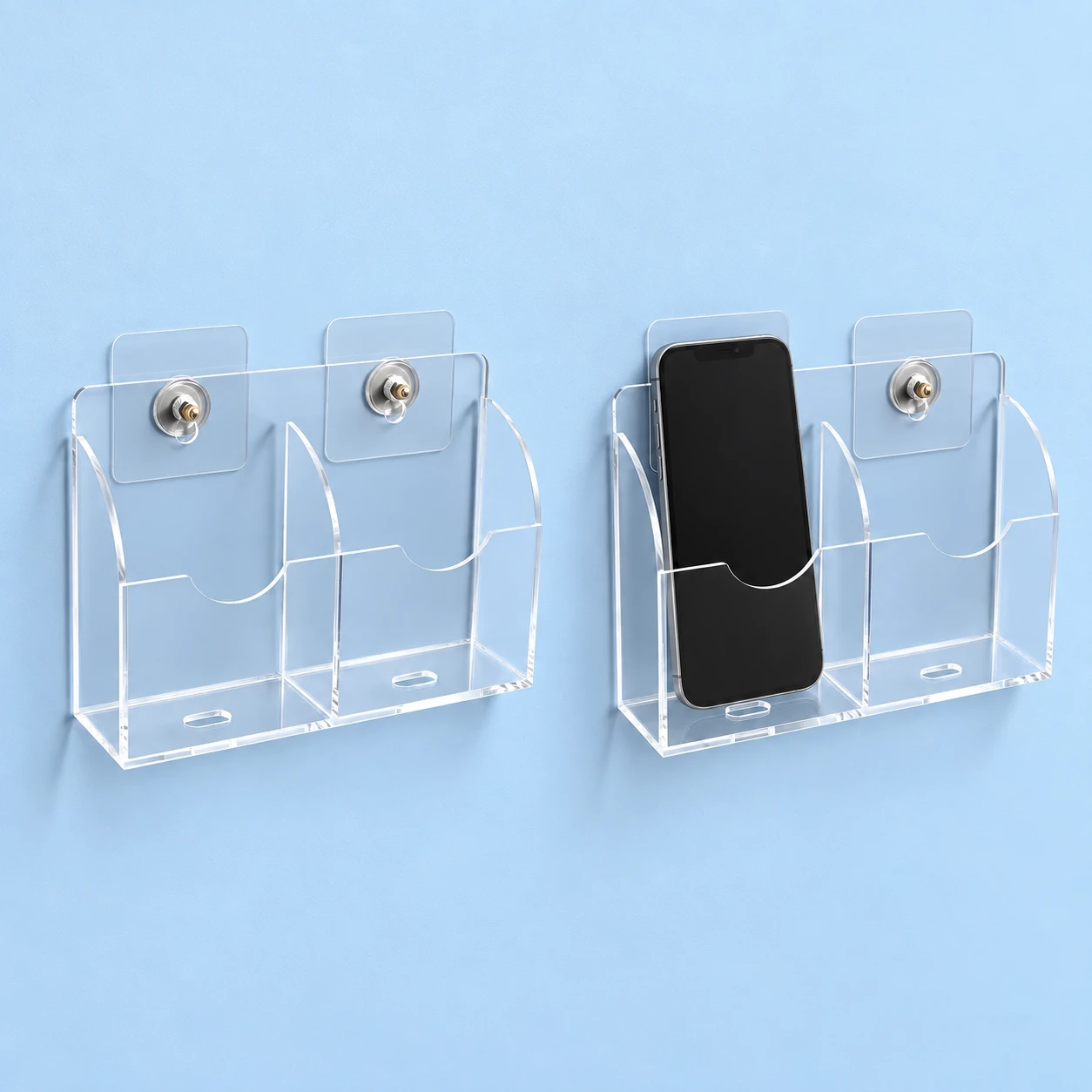 Complete clear two-bay wall phone pocket with its two mounting pads and threaded fittings on the left, and the same holder storing one upright phone in its left bay on the right, against pale blue. Phone shown for context only., square composition