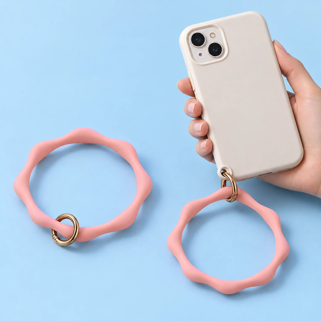 Pastel pink wavy silicone phone wrist loop and original gate attached to a compatible case eyelet