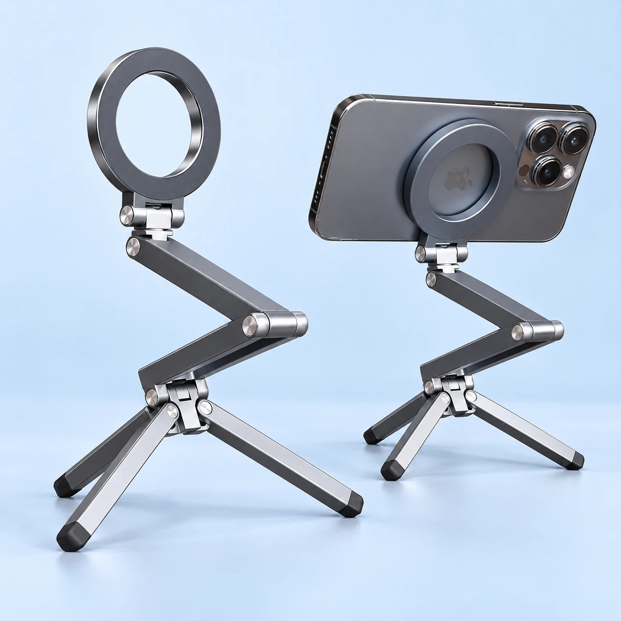 Gray E08 two-link folding magnetic phone tripod shown complete without a phone on the left and supporting a compatible demonstration phone at the back on the right, against pale blue.
