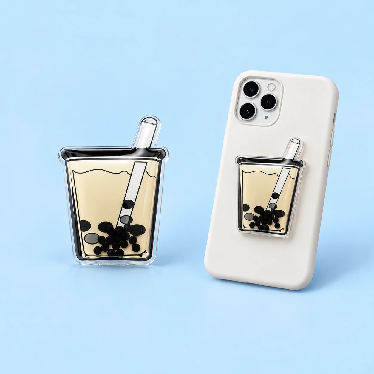 Cream boba cup-shaped phone grip with black pearl details and a projecting straw, square composition
