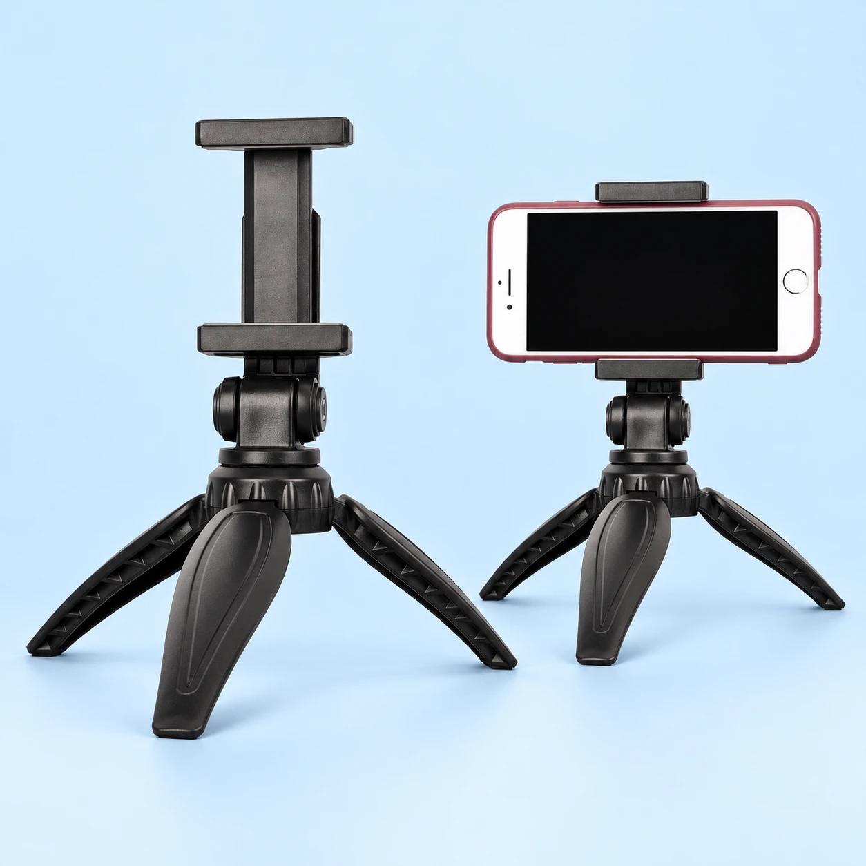 Black leaf-leg mini phone tripod with its empty padded clamp on the left and stationary landscape phone use on the right, on pale blue.