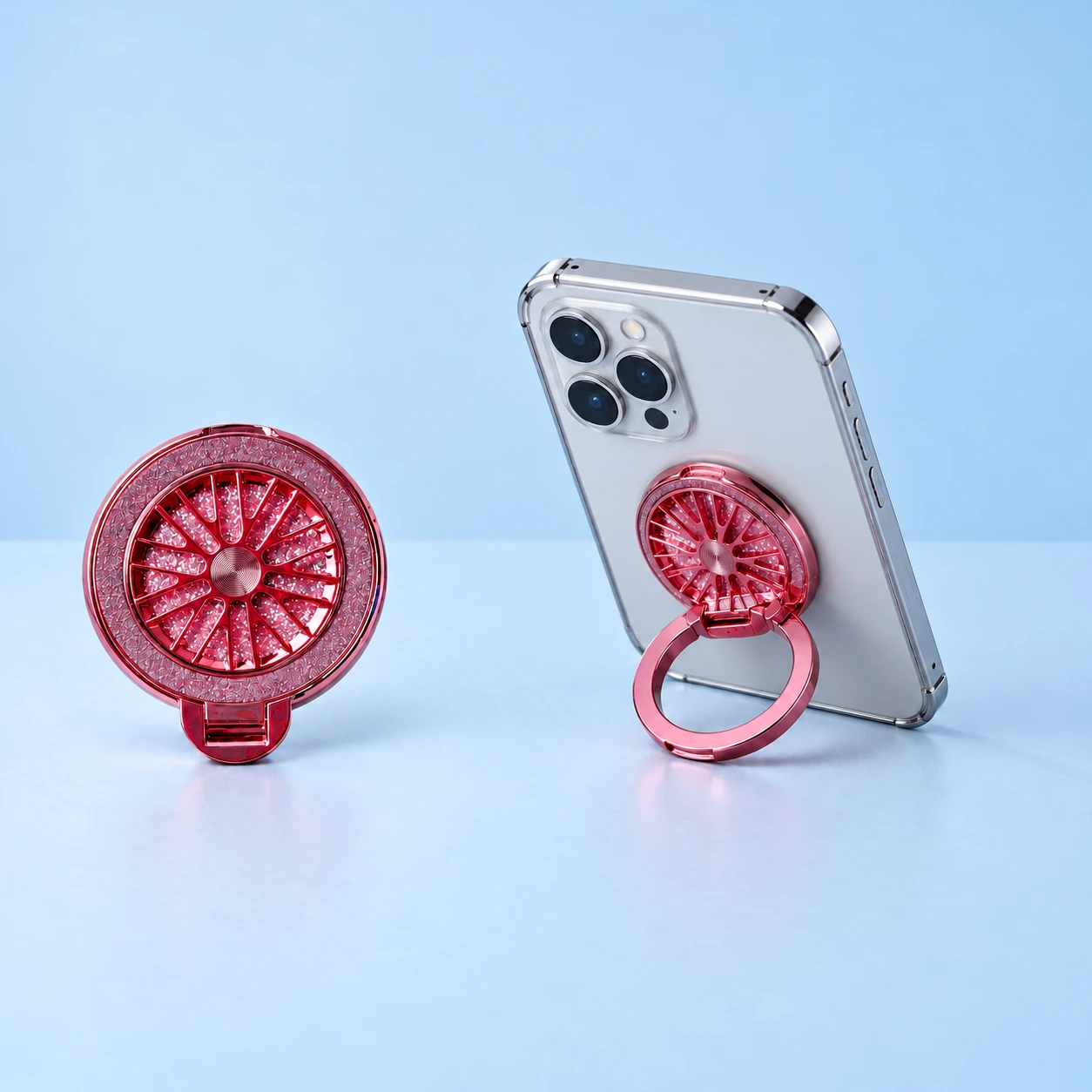 Pink glitter radial-spinner phone ring stand, complete closed product left and original outer ring supporting a phone right on pale blue; phone not included., square composition