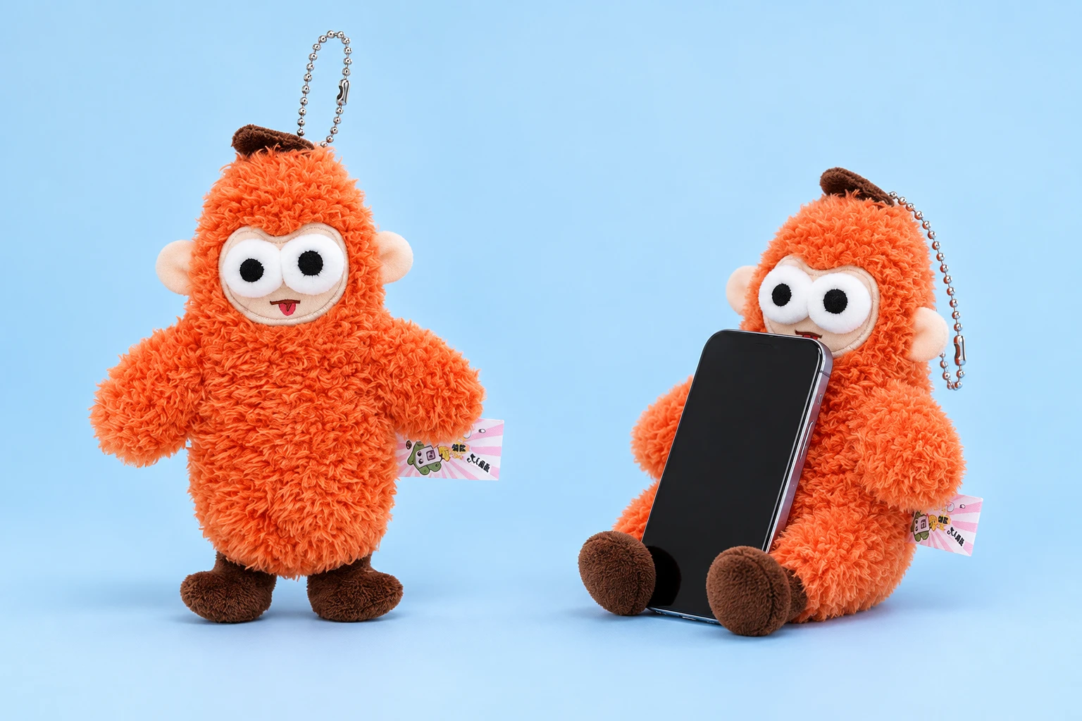 Orange round-eared monkey plush phone rest with decorative ball chain shown complete and supporting an illustrative phone