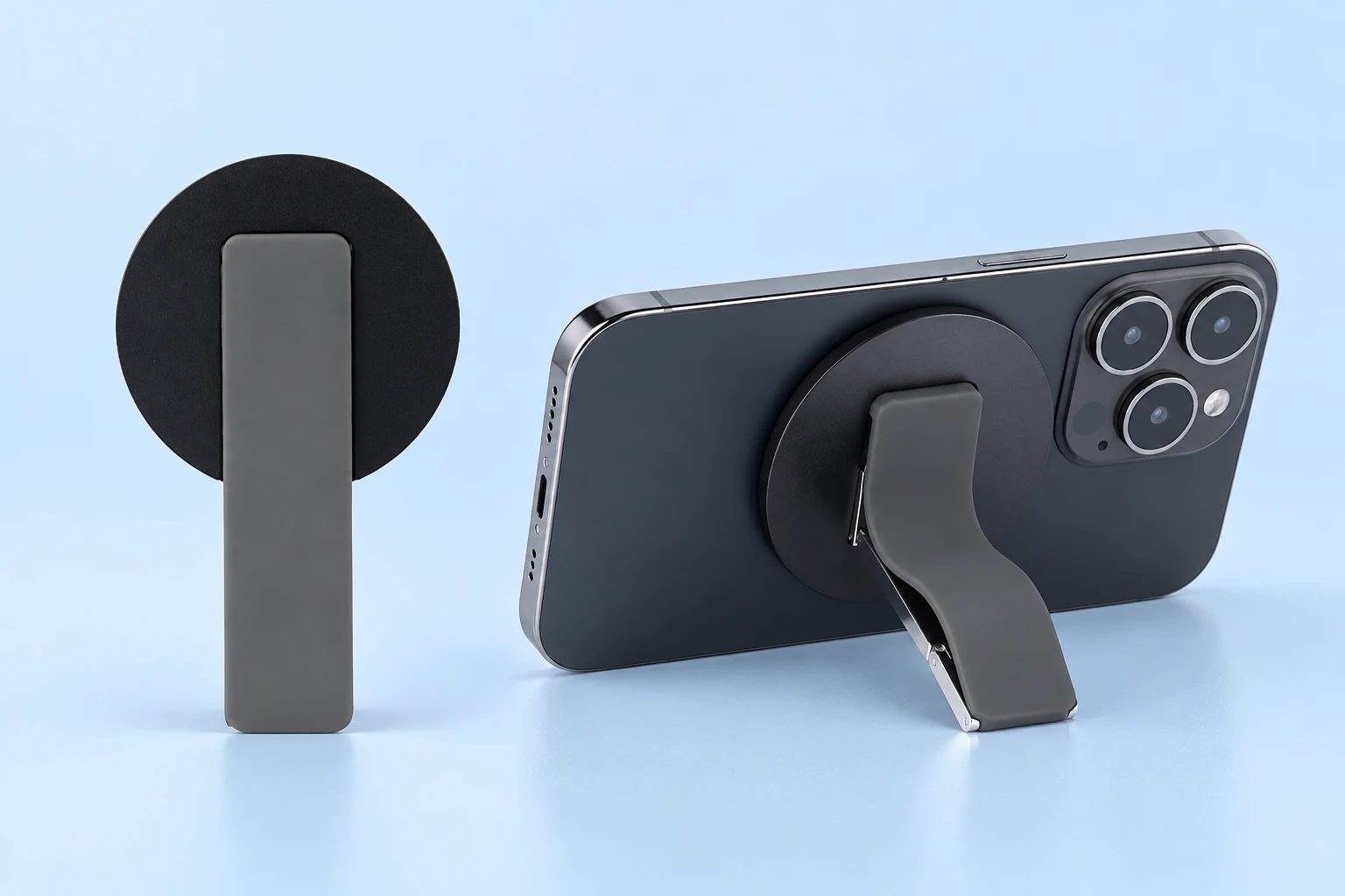 Gray magnetic folding finger band shown folded on the left and supporting a landscape phone from behind on the right, on pale blue.