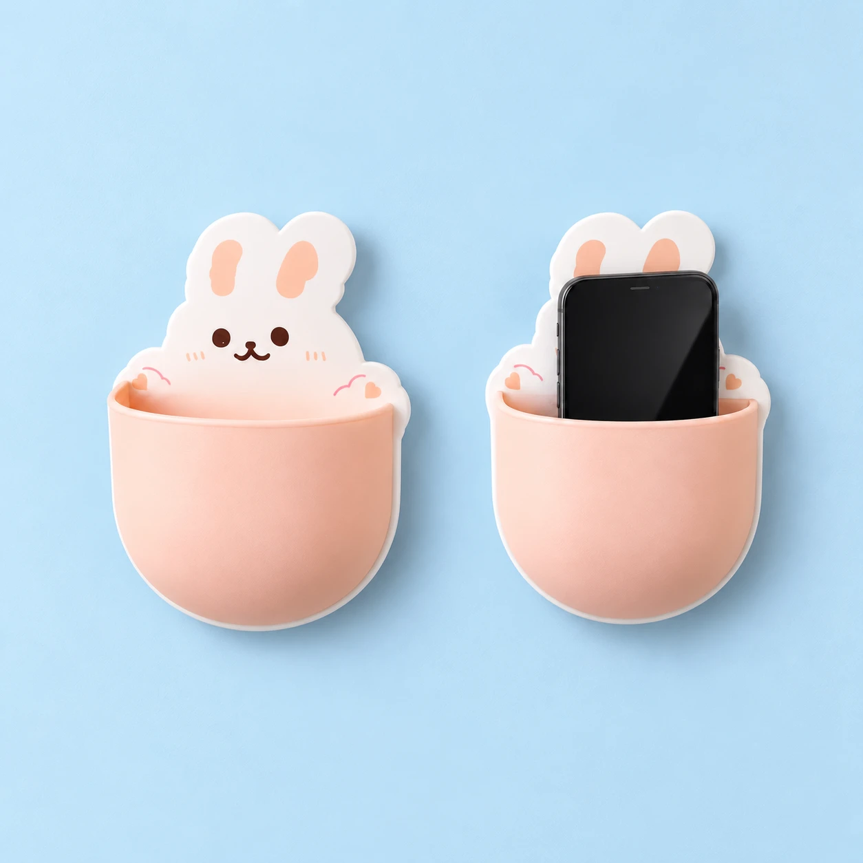 White rabbit-shaped wall phone pocket with peach pink curved front shown empty and holding an illustrative phone, square composition