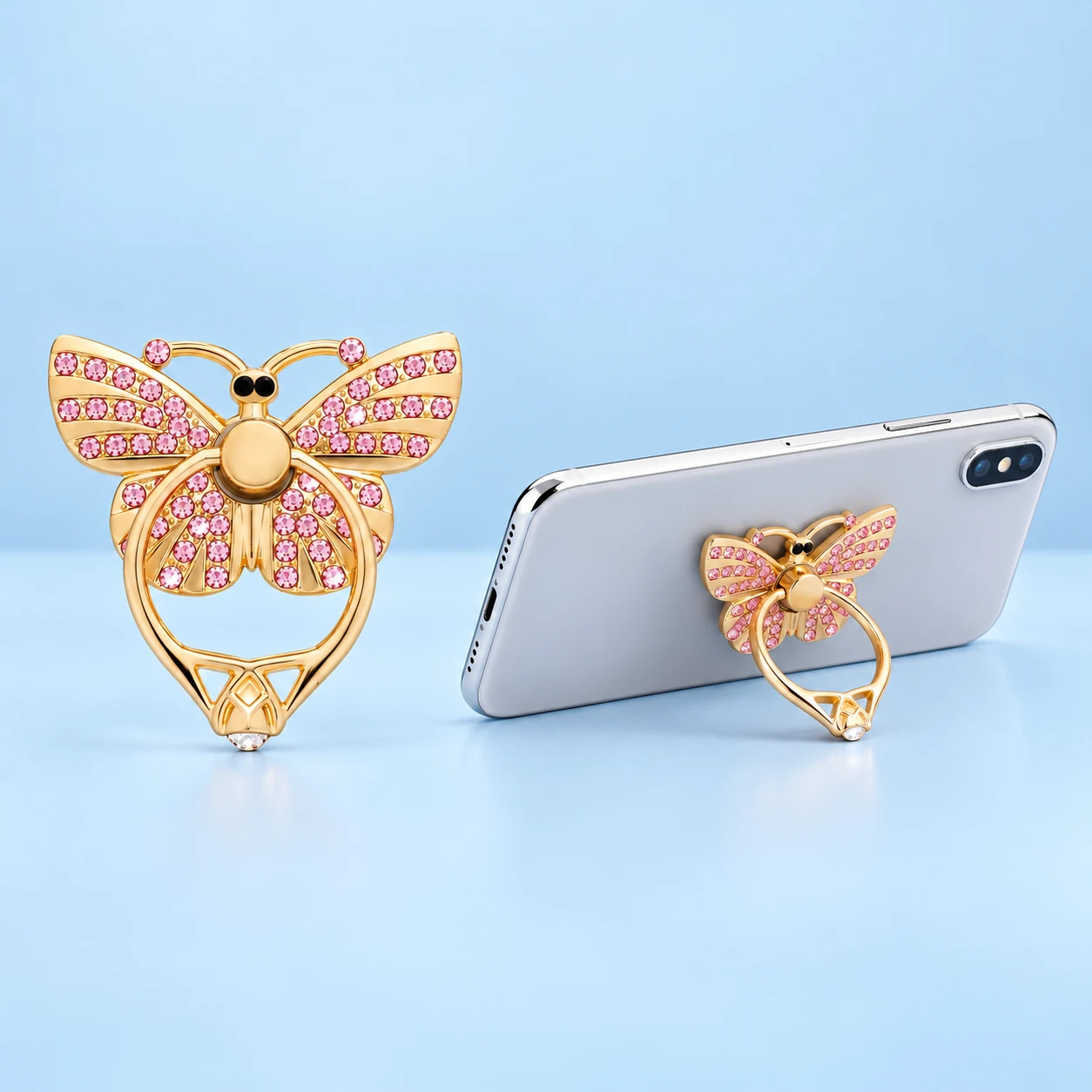 Gold-tone sculpted butterfly phone ring with pink decorative stones, complete and in a same-model landscape-phone use illustration, square composition