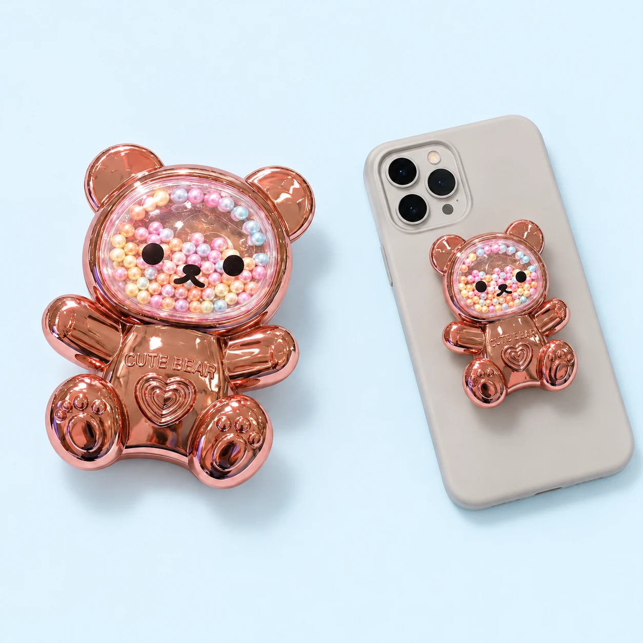 Rose-gold-tone seated bear phone grip with contained pastel beads and CUTE BEAR lettering, square composition