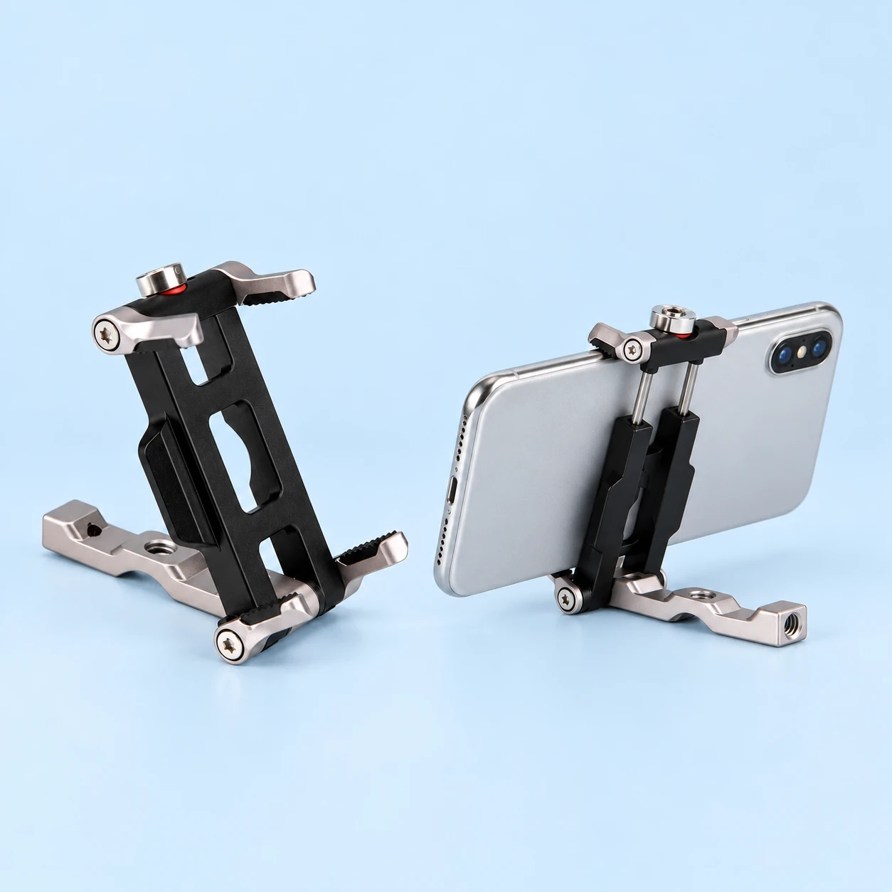 Complete black-and-silver folding phone clamp on its own silver support foot at left; same clamp holding a landscape demonstration phone in a faithful stationary tabletop pose at right. Phone is not included., square composition