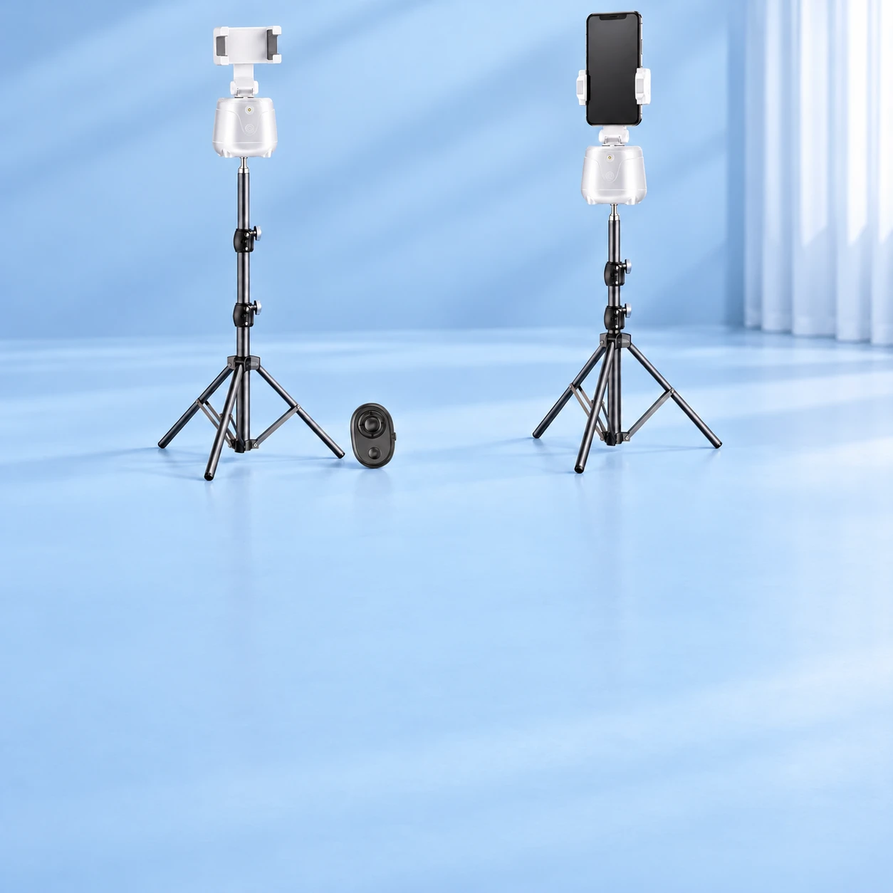 Complete white tracking pod with its original empty clamp, braced tripod and oval remote at left; the same kit holds a stationary portrait demonstration phone at right on pale blue. Phone not included., square composition