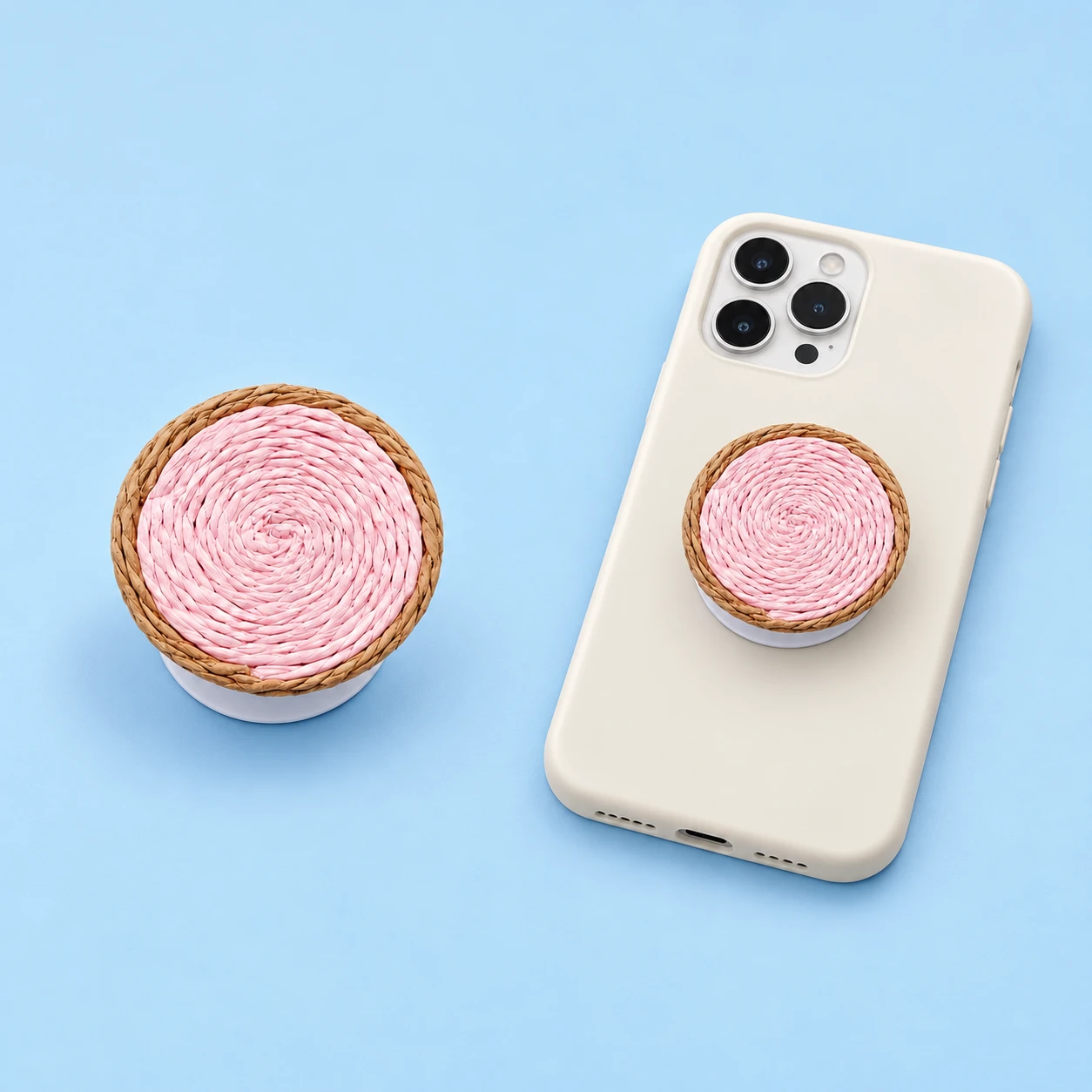 Pale pink coiled-woven phone grip with tan border and closed white base on a phone case, square composition