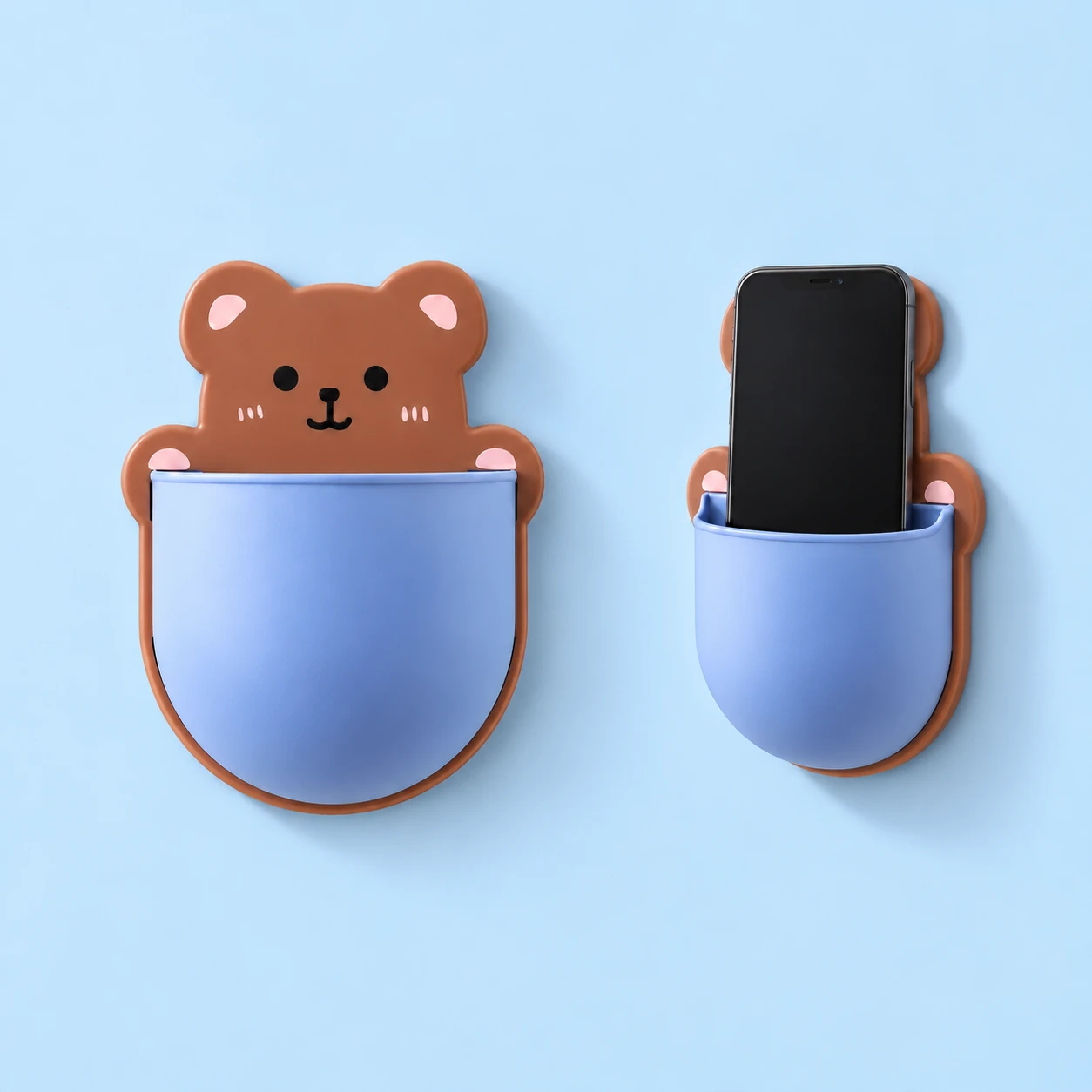 Brown bear-shaped wall phone pocket with blue curved front shown empty and holding an illustrative phone, square composition