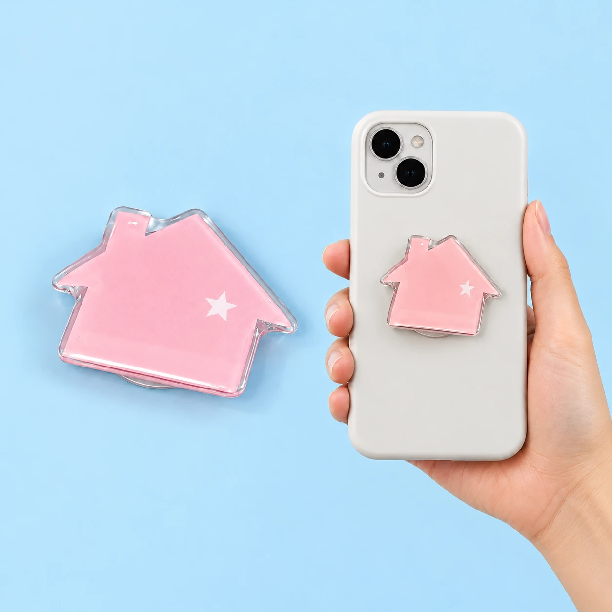 Pastel pink house-shaped phone grip with clear border and white star shown complete and in a closed phone-case placement illustration, square composition