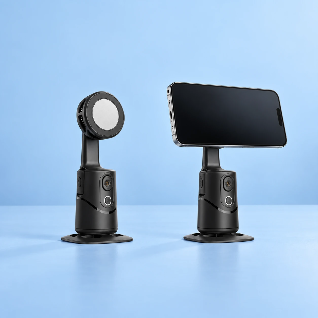 Complete black tabletop tracking holder with its original circular magnetic phone-contact head at left; the same offset-upright holder supports a stationary landscape demonstration phone at right on pale blue. Phone is not included., square composition