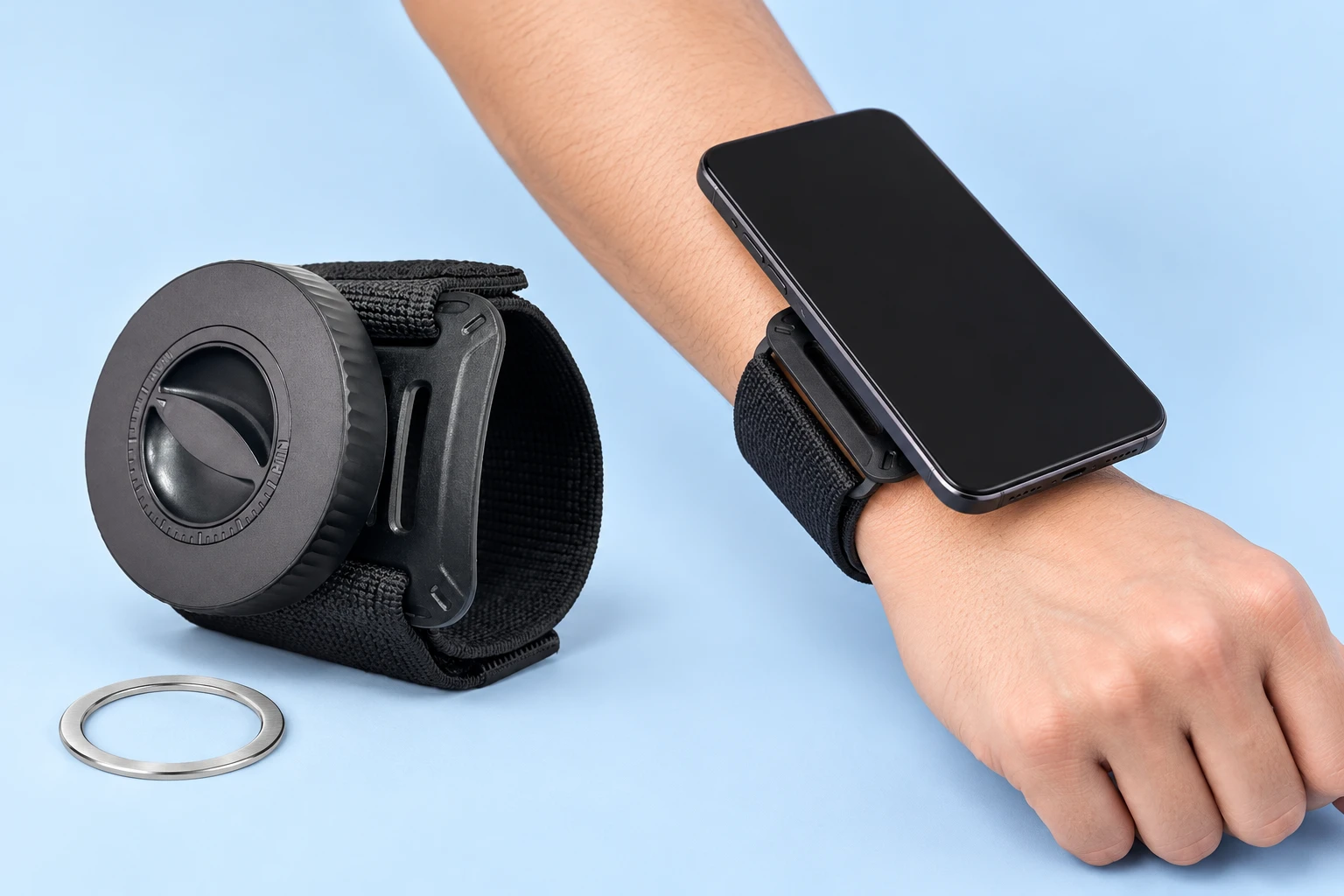 Black wide-cuff magnetic wrist phone holder and supplied receiver ring on pale blue, with illustrative stationary wrist-mounted phone use
