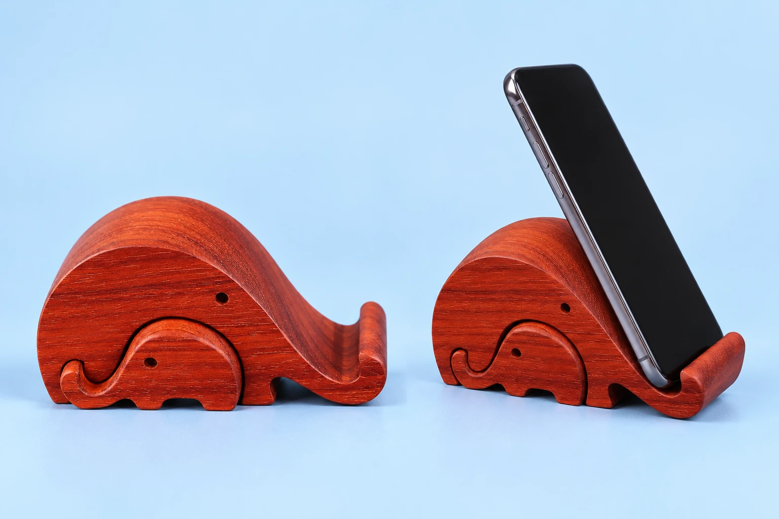 Nested parent and baby wooden elephant phone stand shown complete and with a phone supported by the parent elephant