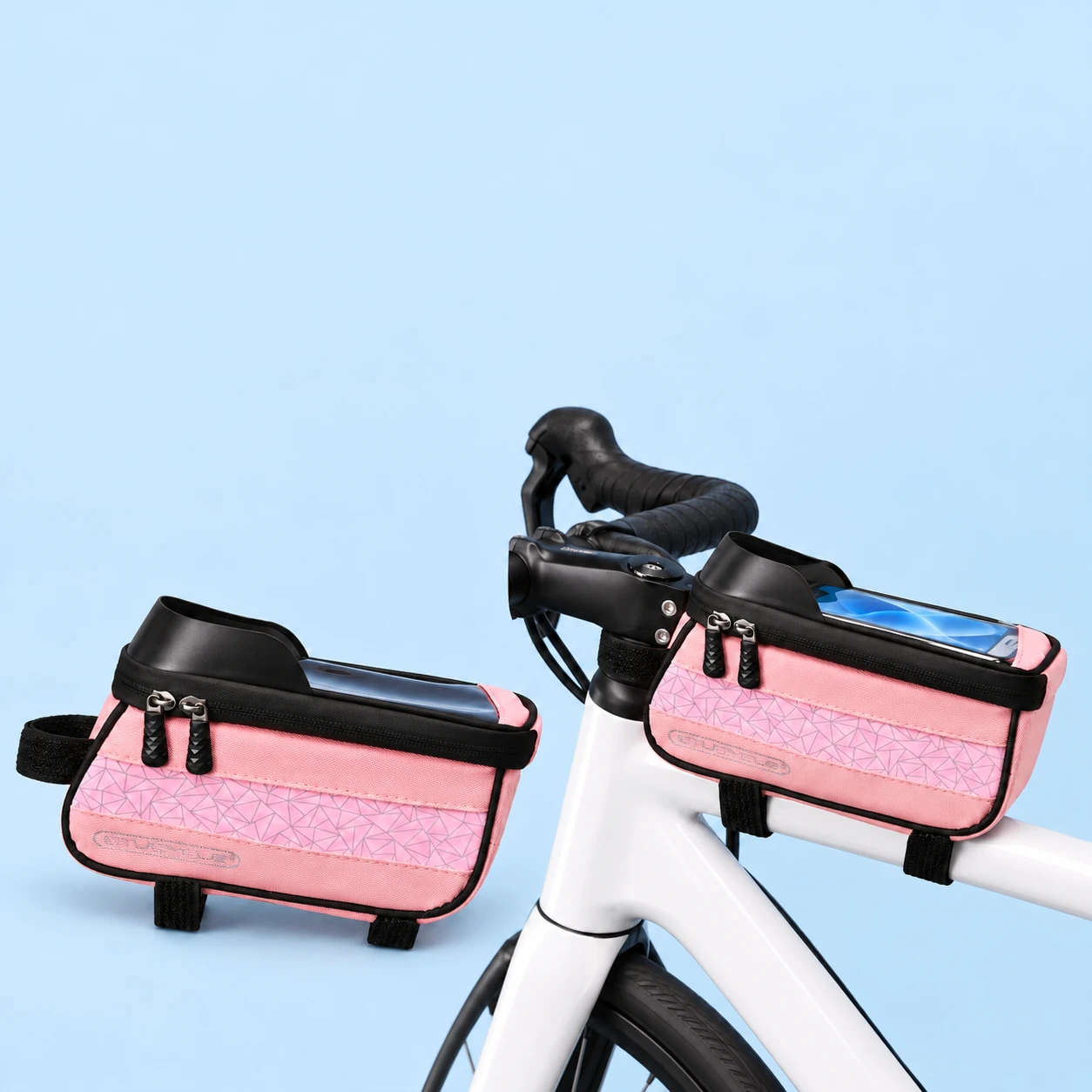 Complete pink geometric top-tube phone-window bag with its three original black wraps at left, and the same bag with a demonstration phone on a stationary white bicycle top tube at right, on a pale-blue background., square composition