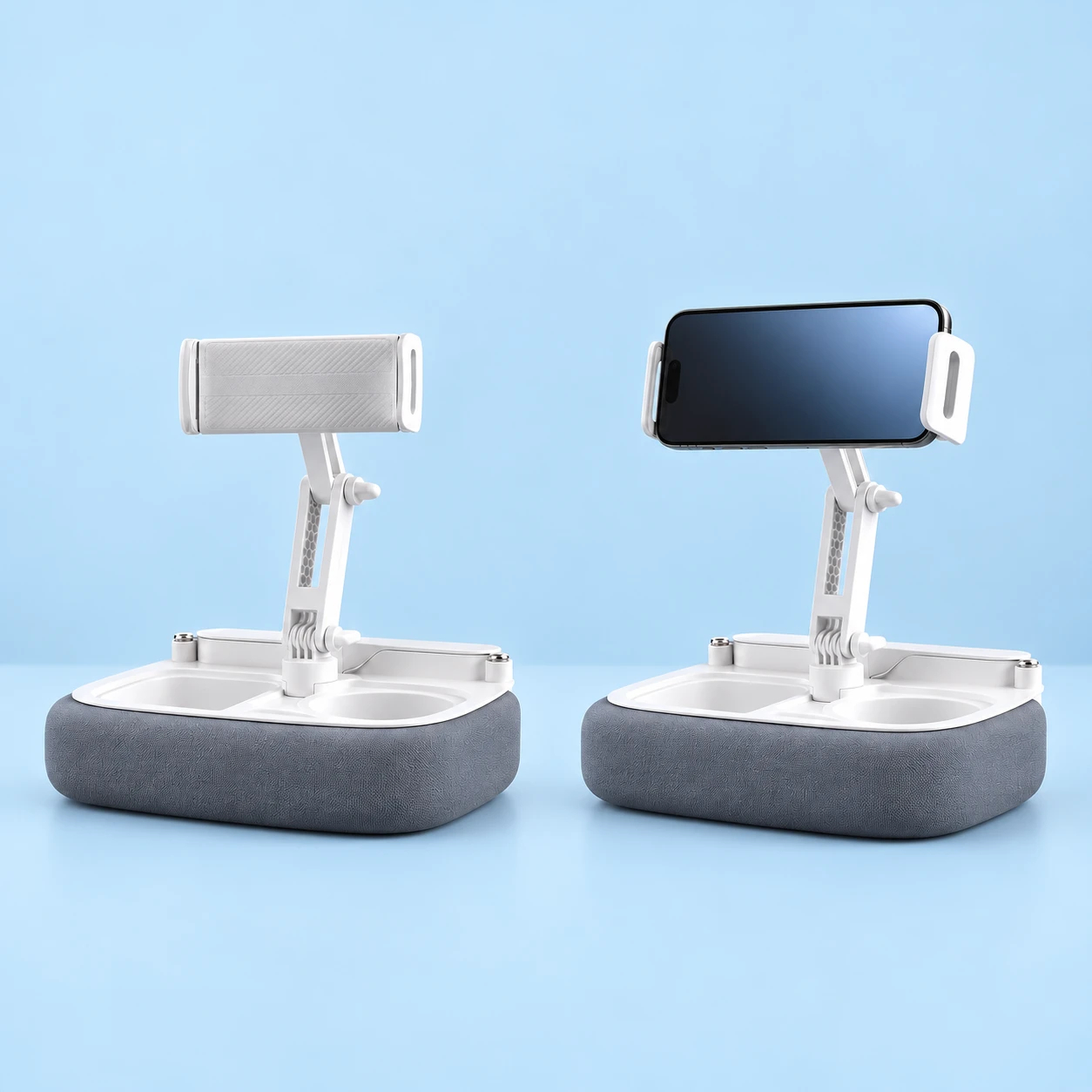 Gray rectangular padded-tray phone stand with a white two-link articulated arm and rectangular end-jaw holder on pale blue, shown empty at left and holding a demonstration landscape phone on a tabletop at right. Phone and tabletop are not included., square composition