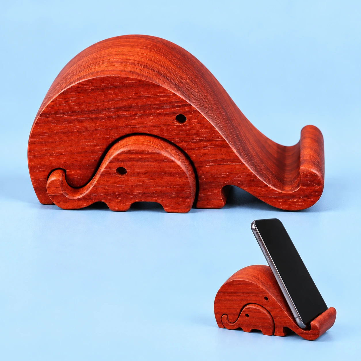Nested parent and baby wooden elephant phone stand shown complete and with a phone supported by the parent elephant