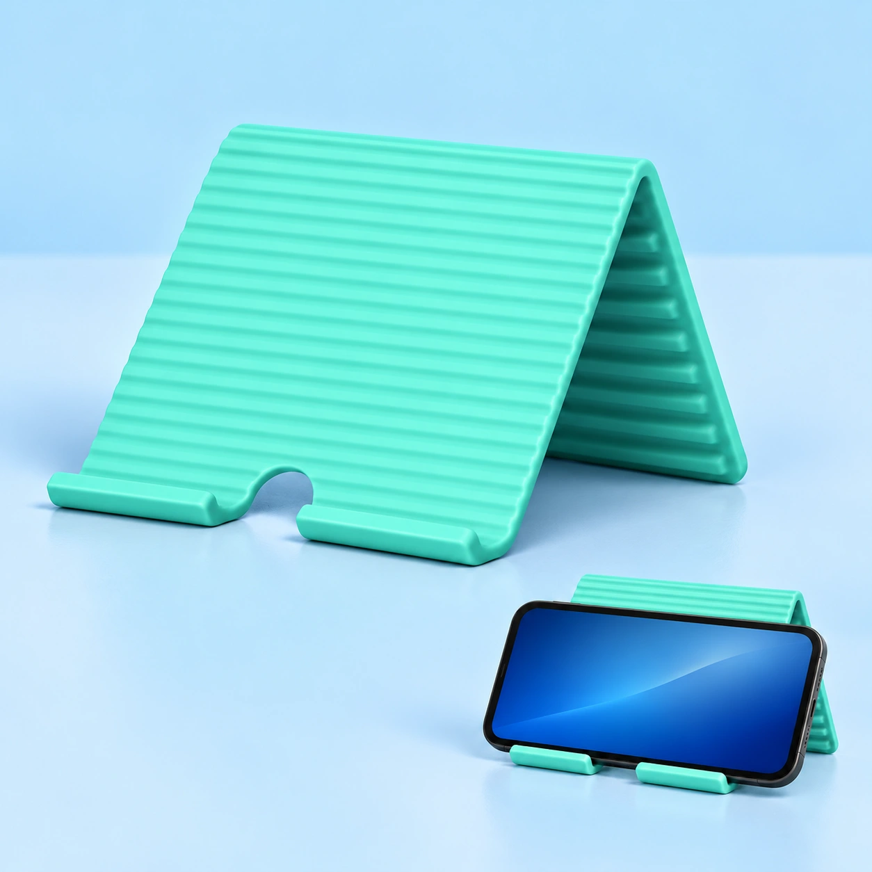 Mint flexible silicone phone stand shown folded and supporting a landscape phone on its split front lip