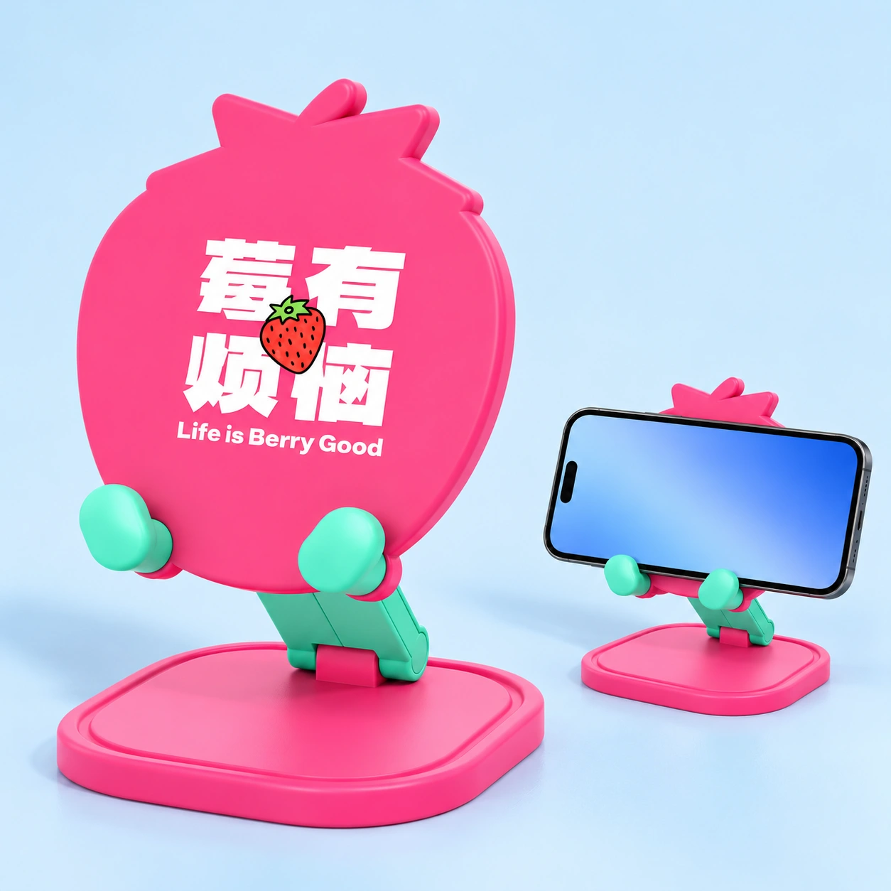 Pink strawberry folding phone stand, complete stand left and landscape phone in mint cradle lips right; phone not included