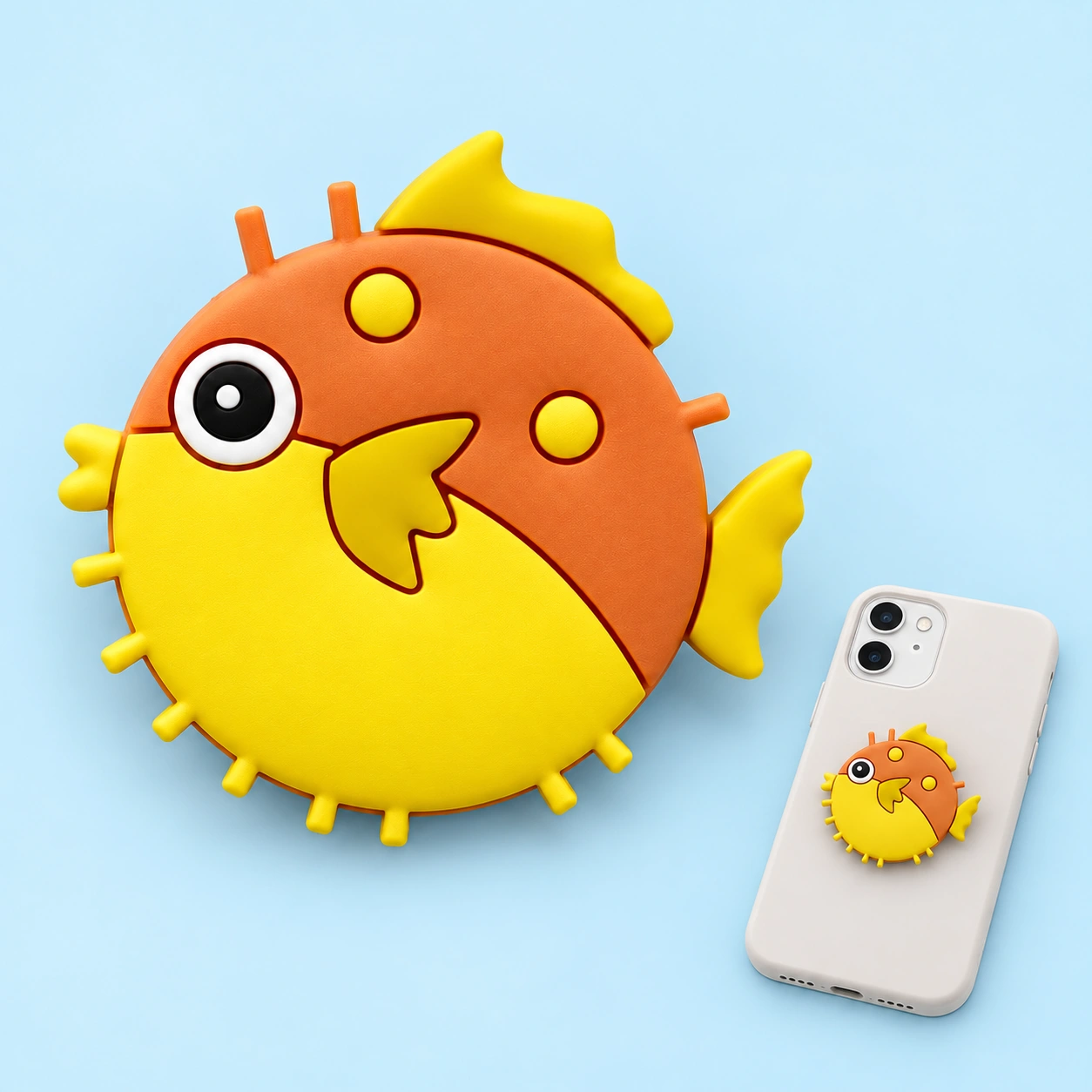 Yellow and orange pufferfish phone grip shown complete and mounted flat on a phone case